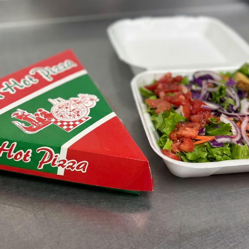 Fresh Hot Pizza box beside a takeaway salad with lettuce, tomatoes, onions, carrots, and breaded chicken pieces.